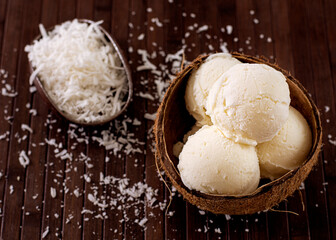 Coconut ice cream in natural coconut shell with grated coconut decoration in the background