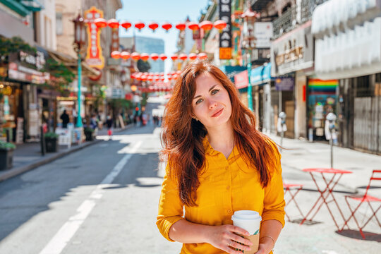 A young woman in a yellow shirt walks along a Chinese street in downtown San Francisco. A festive beautiful street with lanterns in the afternoon