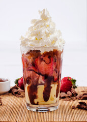 Brazilian strawberry dessert in the glass with ingredients and strawberries in the background decoration