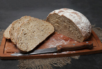 Homemade bread from coarse flour with spices, with flax and sunflower seeds cut on a wood board. Sourdough yeast bread making, gluten-free diabetic bread