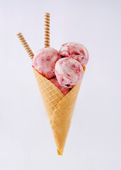 ice cream cone with three strawberry balls on a neutral background