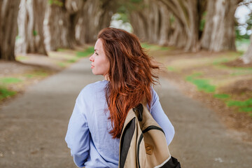 Rear view of a young woman with a backpack in the Cypress Tree Tunnel near San Francisco, USA