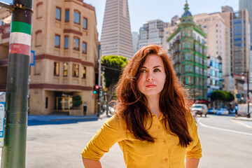 Beautiful young woman in a yellow shirt in a business center with a view of the Transamerica Tower...