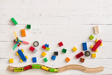Toy wooden train by railroad with rails on the background of a white wooden table. Multi-colored...