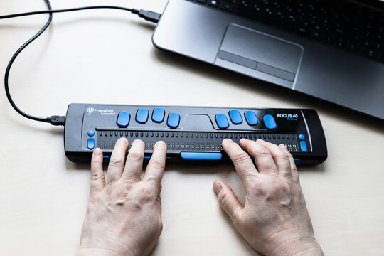 Moscow, Russia - June 5, 2021: reading with Focus 40 Blue Braille Display. Freedom Scientific is the largest manufacturer of assistive technology products for blind and low vision people