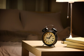 Naklejka premium Alarm clock with books on table in bedroom at night