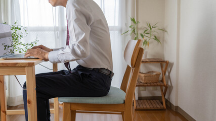 姿勢の悪い男性。家で仕事するビジネスマン。
