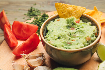 Bowl with tasty guacamole and nacho on table, closeup