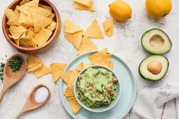 Bowls with tasty guacamole and nachos on light background