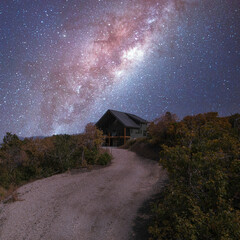 Fototapeta na wymiar Square frame Path in the middle of a shrubland leading to a house under an aesthetic composite milky way