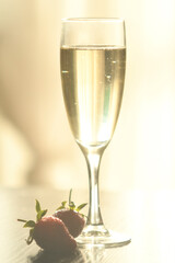 A glass of sparkling champagne. Strawberries are lying next to me in a glass. Pastel shades. 