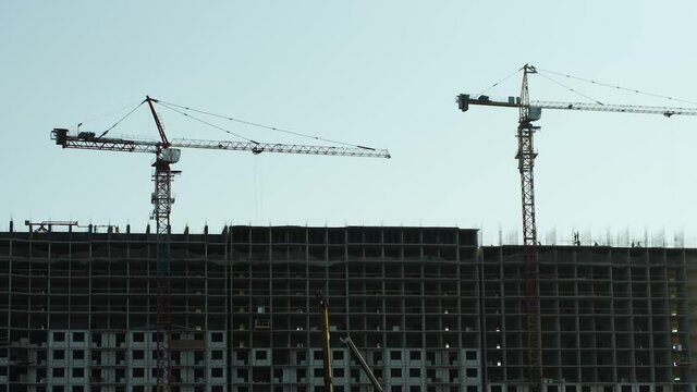 Construction of a high-rise building. On the construction site, the movement of cranes and people. The concept of affordable housing construction