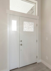 Vertical Interior of a white wooden front door with side panel and top transom window