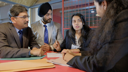 Sikh man wearing the black turban with his colleagues from India in the workplace having a meeting