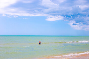 Fototapeta na wymiar Beautiful azure sea and blue sky on the horizon. A man in the water in the background. Idyllic sea landscape