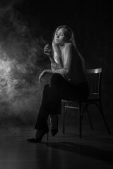 A girl in a white blouse is sitting on a chair with a cigarette in her hands, there is smoke around. Depression, feminism, loneliness, strong woman, independent, thoughts, reflections, bad habits