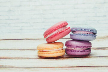 Multicolored macarons on a table and white wall background