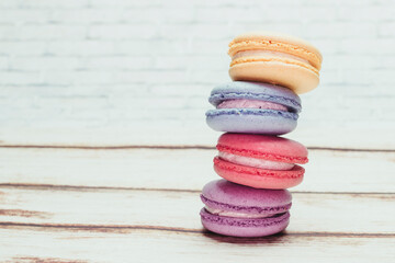 Fototapeta na wymiar Multicolored macarons on a table and white wall background
