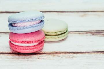 Multicolored macarons on a table and white wall background
