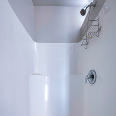 Square frame Shower area with a knob and rack under the shower head.