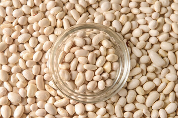 Glass bowl on raw beans, closeup