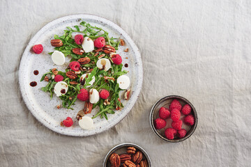 Summer salad with arugula, raspberries, mozzarella cheese and pecan nuts. Morning, breakfast, healthy food. Selective focus