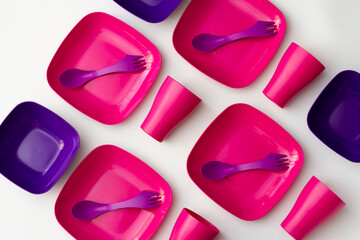 Purple plastic plates and forks with a spoon on a bluish background