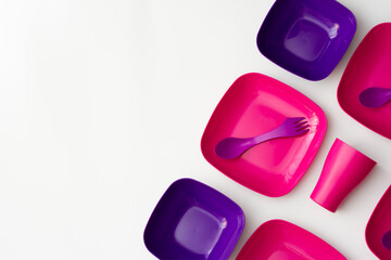 Purple plastic plates and forks with a spoon on a bluish background