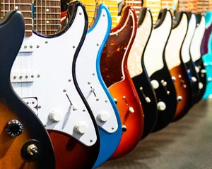 Abwaschbare Fototapete Musikladen Reihe von E-Gitarren unterschiedlicher Farbe in einem Musikinstrumentenladen
