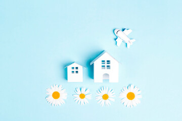 Small toy houses and  airplane with chamomiles on a blue background.