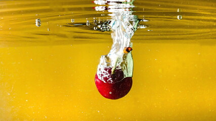 ripe cherries fall into the water raising splashes and air bubbles