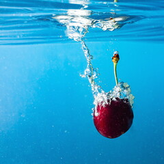 ripe cherries fall into the water raising splashes and air bubbles