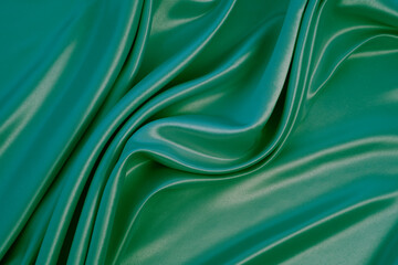 Beautiful elegant wavy green satin silk luxury cloth fabric texture with monochrome background design. Copy space