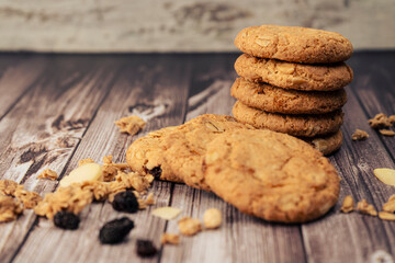 Stack of homemade oatmeal cookies with raisins and seeds, raisins and cereal dumped on the table. Natural nutrition concept.