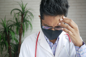 Depressed sad doctor covering face with hands 
