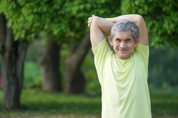  elderly retired man is warming up exercise before running or jogging in the park, concept warm up exercise prevent injury in elderly people