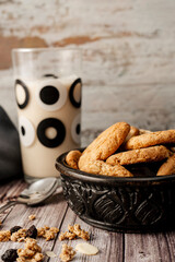 Bowl with homemade oatmeal cookies with raisins and seeds and a glass of milk behind. Portrait orientation. Natural nutrition concept.