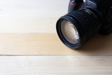 Overhead shot of a reflex camera on a wooden table positioned in the upper right corner.