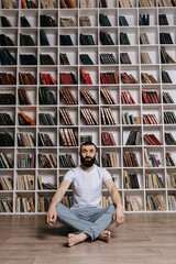 A brutal man sitting on the floor in meditation in the library