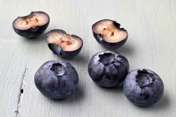 Several cut blueberries on a wooden blue background