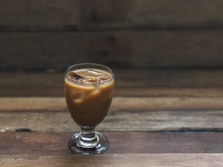 Wine glasses has iced latte coffee on empty old wood table top,dimly light,free space for text design.Concept of Relaxation in Coffee time.