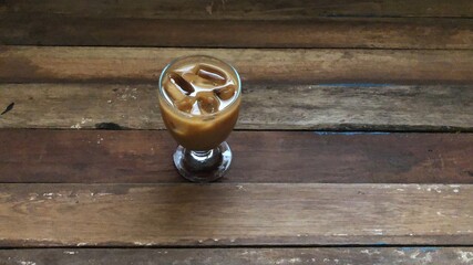 Wine glasses has iced latte coffee on empty old wood table top,dimly light,free space for text...