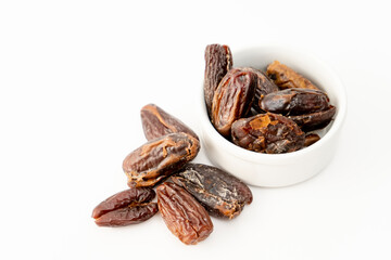 Fresh dates in a small white bowl on a white surface. Concept healthy and natural food