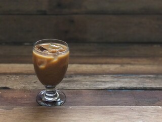 Wine glasses has iced latte coffee on empty old wood table top,dimly light,free space for text design.Concept of Relaxation in Coffee time.