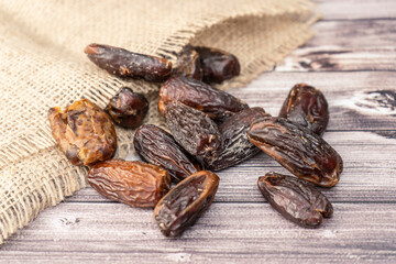 Aerial view of fresh dates out of a rustic bag on a wooden table. Concept of natural nutrition, organic fruits, ethnic food.