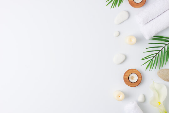 Spa treatment with towel, candles and palm on white background. Flat lay, copy space
