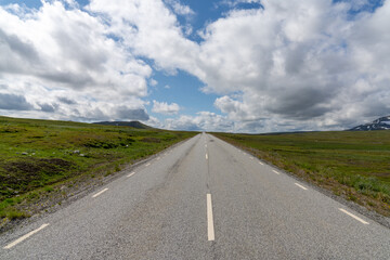 paved highway leads straight to the horizon in a wild tundra landscape