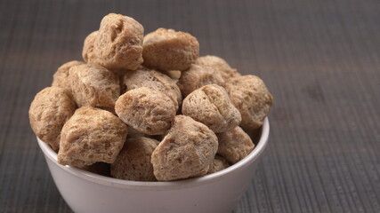 Raw soya chunks on dark background. Healthy, nutritious soybean meat, chunks isolated.Vegan food concept.