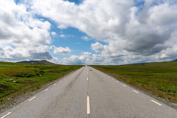 paved highway leads straight to the horizon in a wild tundra landscape