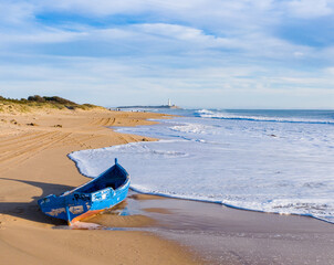 Immigrant and refugee dinghy boat stranded on the shore of a bautiful sand beach in south Spain....